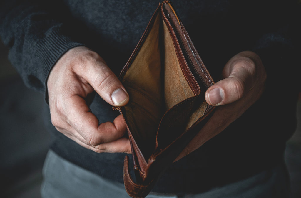 Man opening up wallet with no money inside experiencing poverty