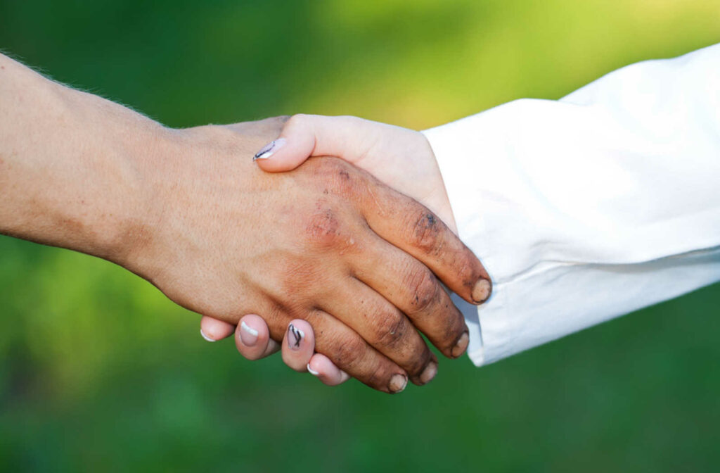 a person wearing a doctors coat hold the hand of a person experiencing homelessness in support
