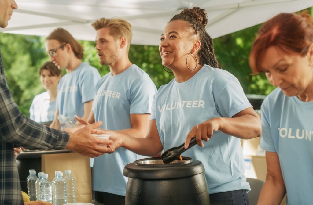 A soup kitchen volunteer giving a bowl of soup to a person who is in need.