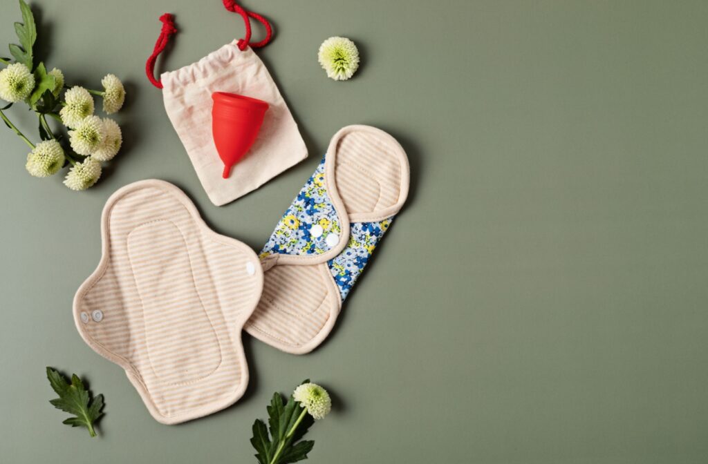 Sanitary pads and menstrual cup for personal hygiene on a green background