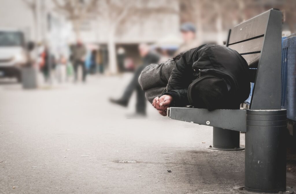 Someone who is experiencing homelessness putting on a mask.