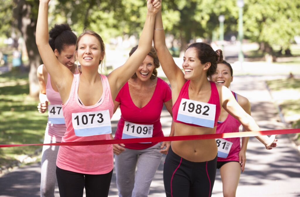 A group of women crossing the finish line of a charity race, celebrating their achievement and fundraising efforts.